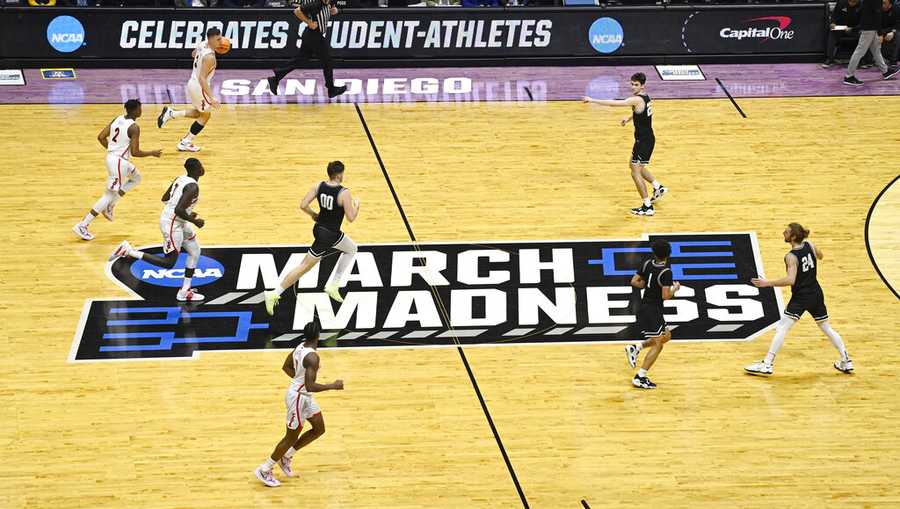 Arizona and Wright State players move past the March Madness logo during the first half of a first-round NCAA college basketball tournament game.