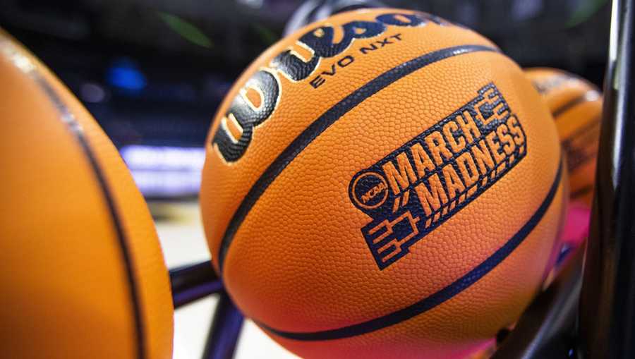 FILE - A basketball with a March Madness logo rests on a rack.